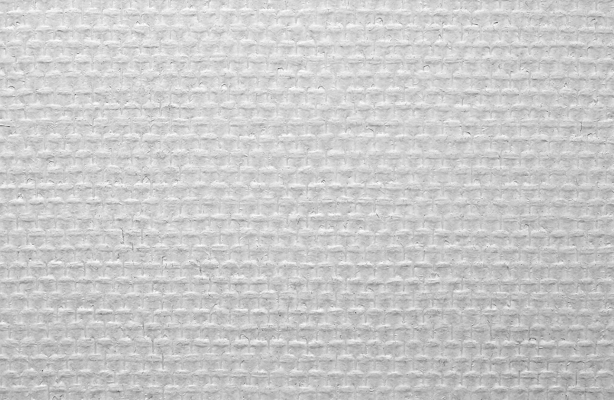 Close-up van wit glasvliesbehang met een fijne, regelmatig geweven structuur.